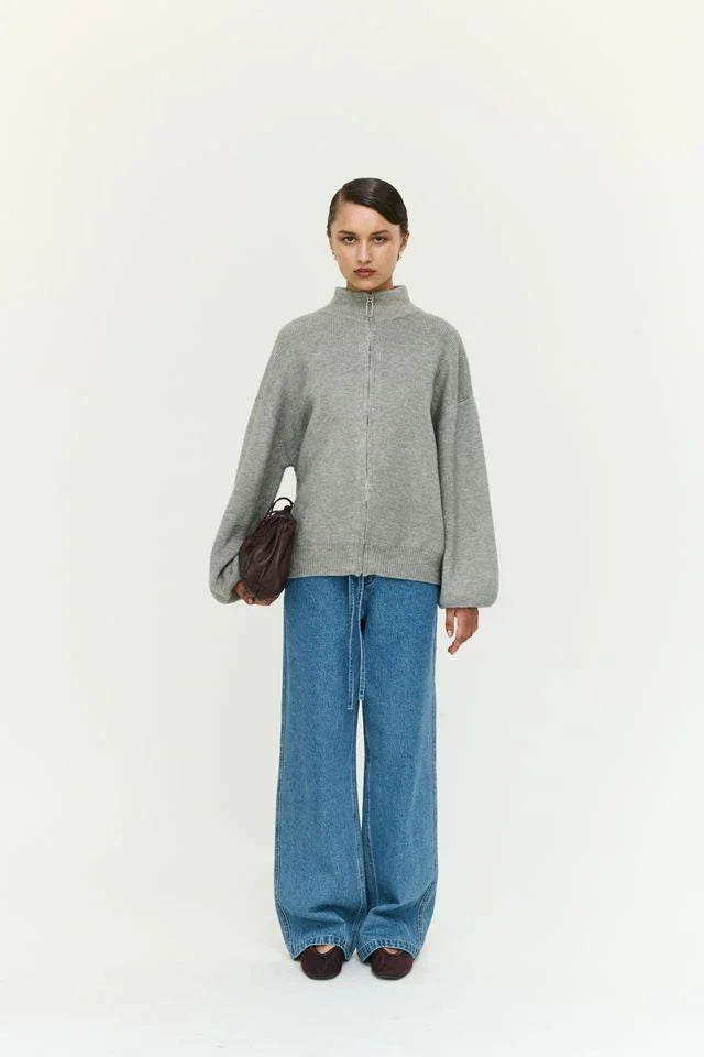 Woman in grey zip-up sweater, wide-leg jeans, and brown bag — women's fashion outfit