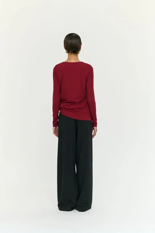 Woman wearing burgundy long-sleeve top and black pinstripe wide-leg pants, back view